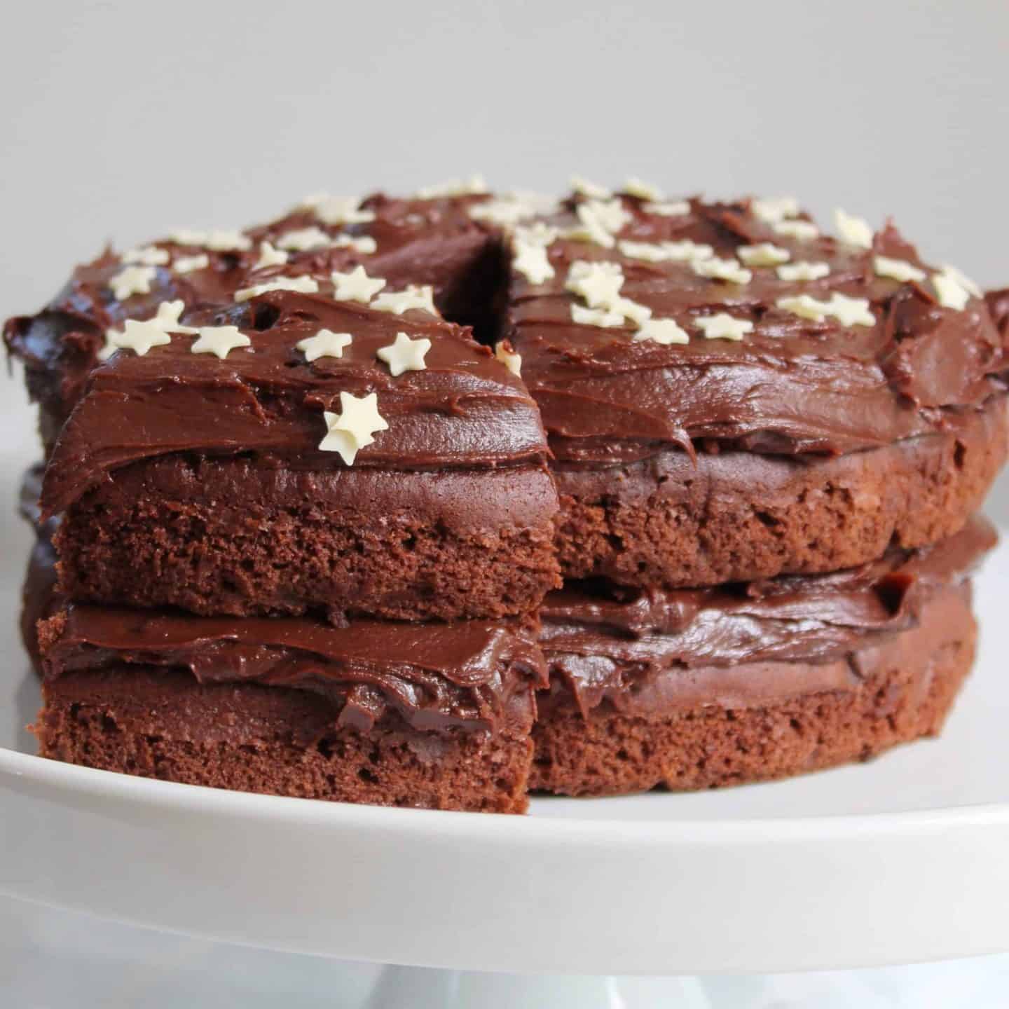 A gluten free chocolate cake topped with chocolate ganache and white chocolate stars.