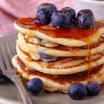 A stack of gluten free blueberry pancakes with syrup.