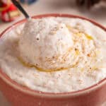 A bowl of gluten free bead sauce with a spoon dunked in, and festive decorations behind.