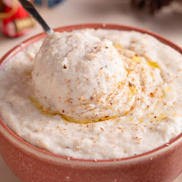 A bowl of gluten free bead sauce with a spoon dunked in, and festive decorations behind.