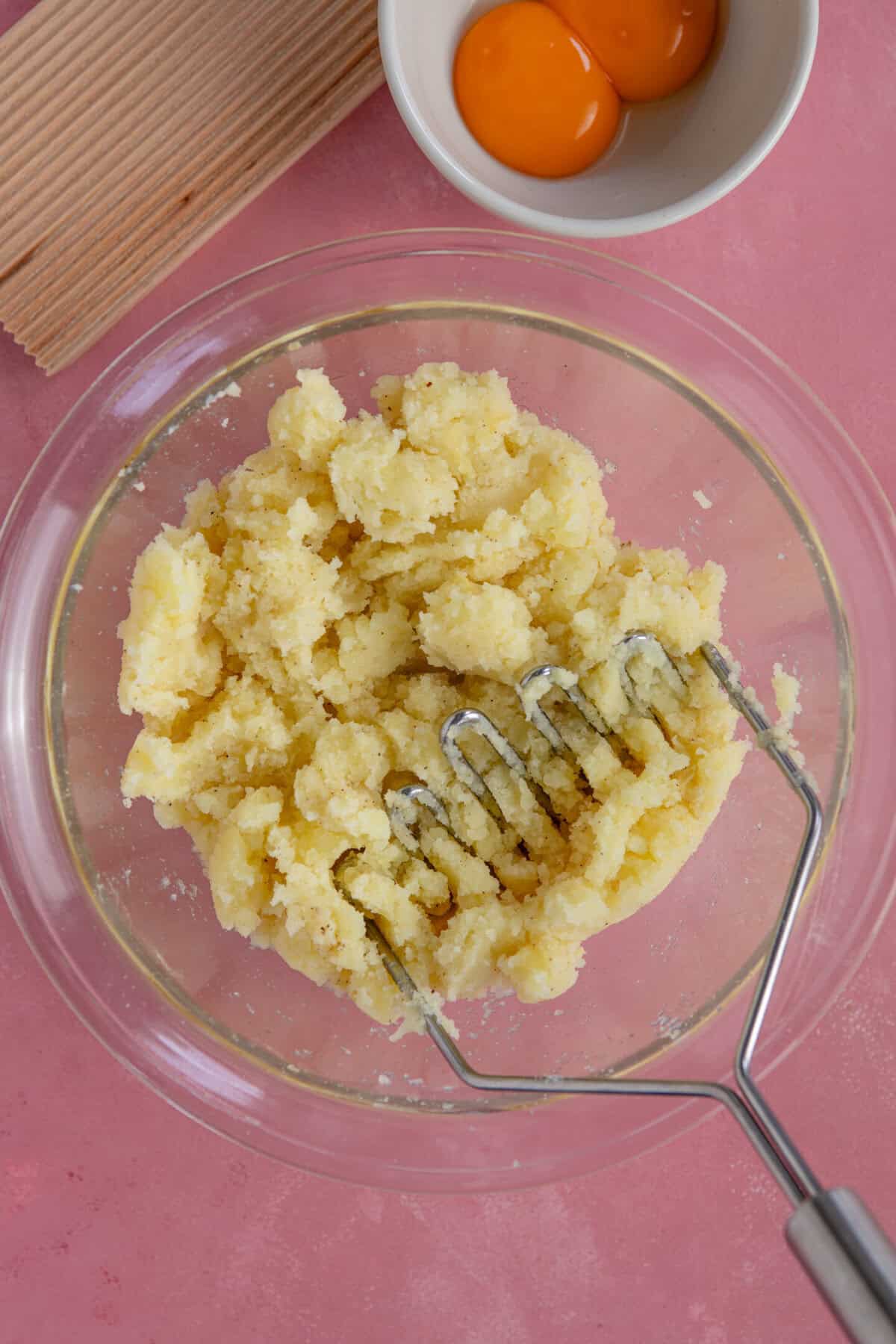 Process shot of gluten free gnocchi recipe showing the mashed potatoes in a glass bowl.
