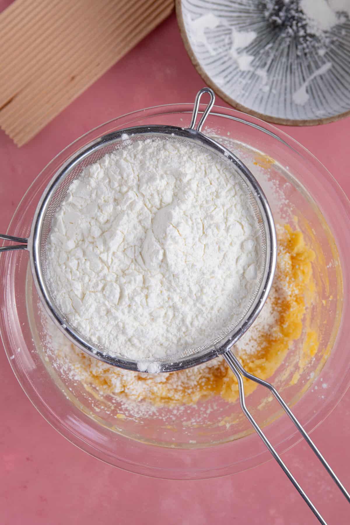 Process shot of gluten free gnocchi recipe showing the flour being sifted into the gnocchi dough.