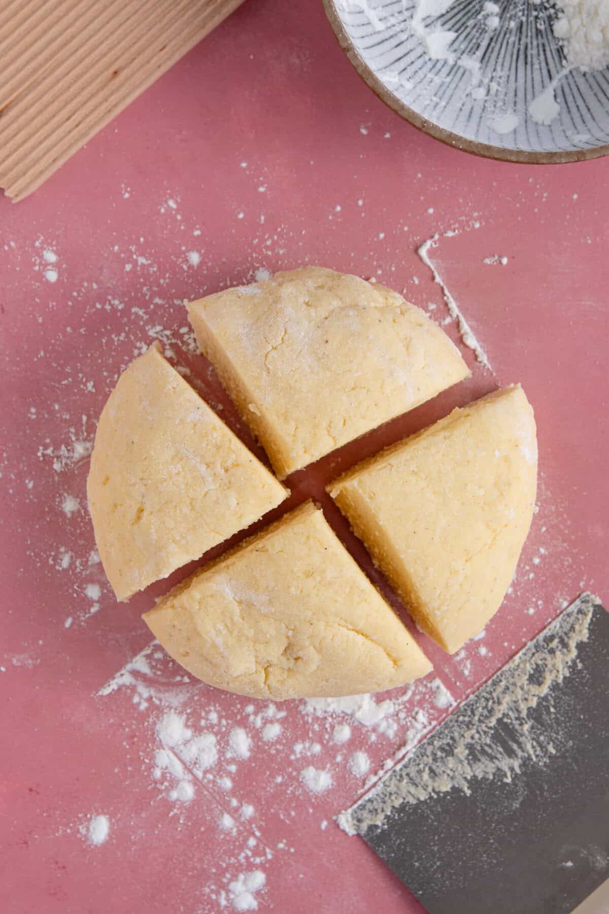 Process shot of gluten free gnocchi recipe showing a ball of gnocchi dough divided into four wedges.