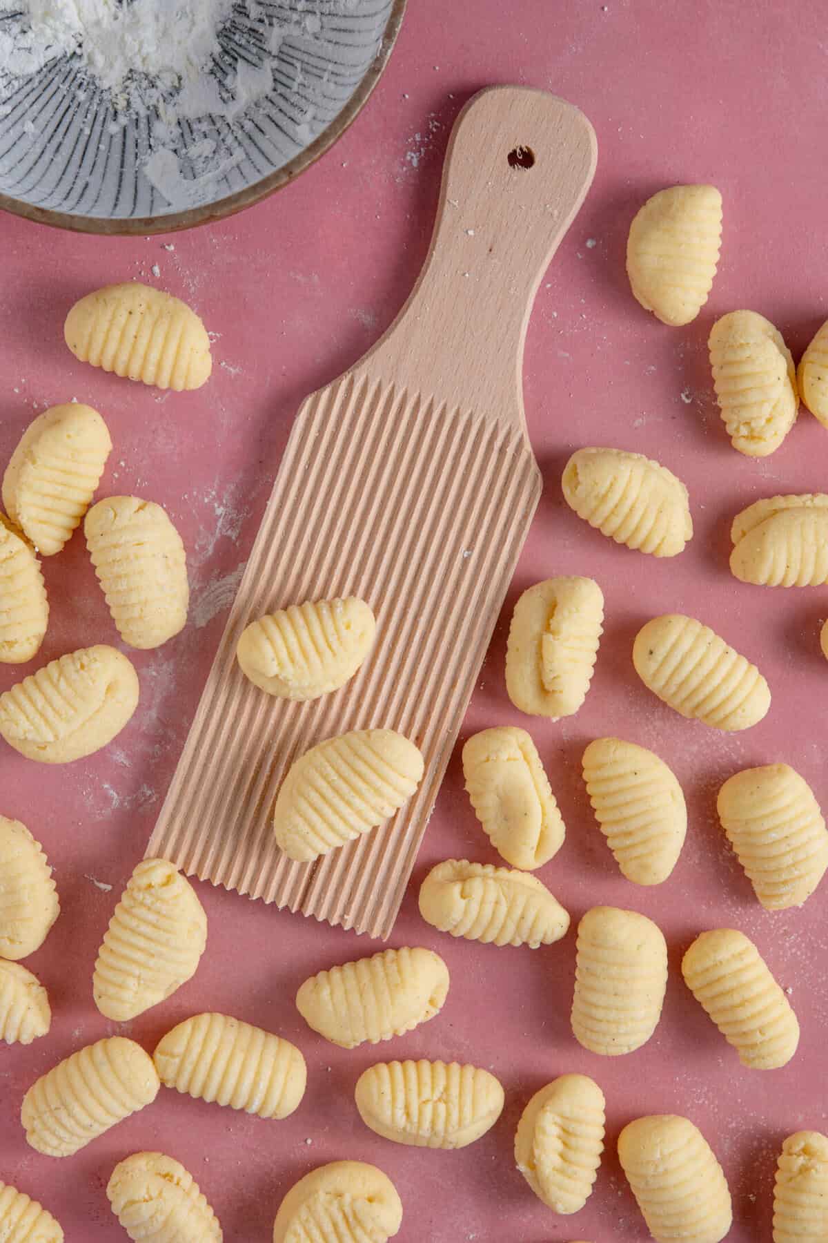 Process shot of gluten free gnocchi recipe showing the gnocchi dough rolled on a gnocchi board.