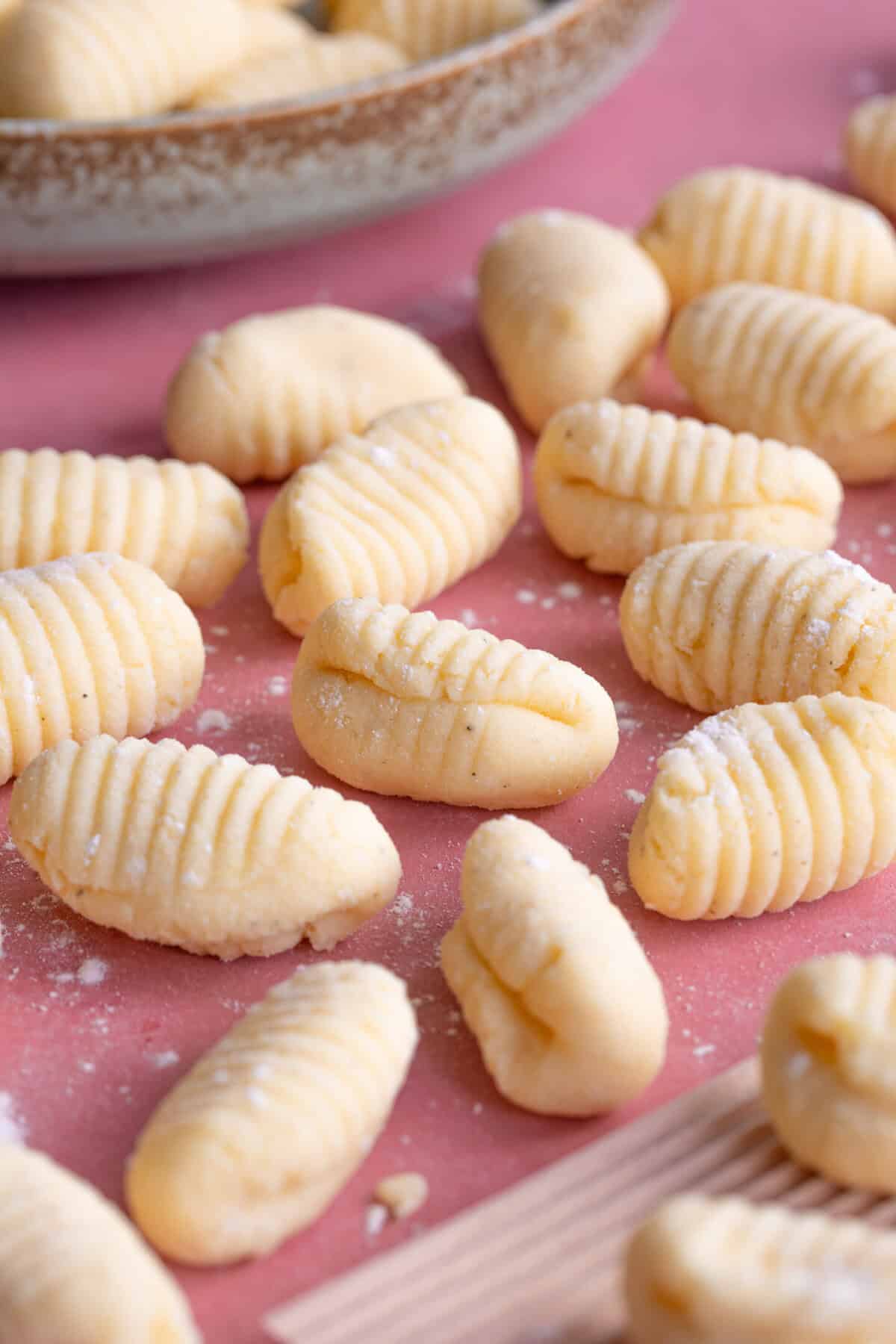 Close up shot of gluten free gnocchi on a pink worktop.