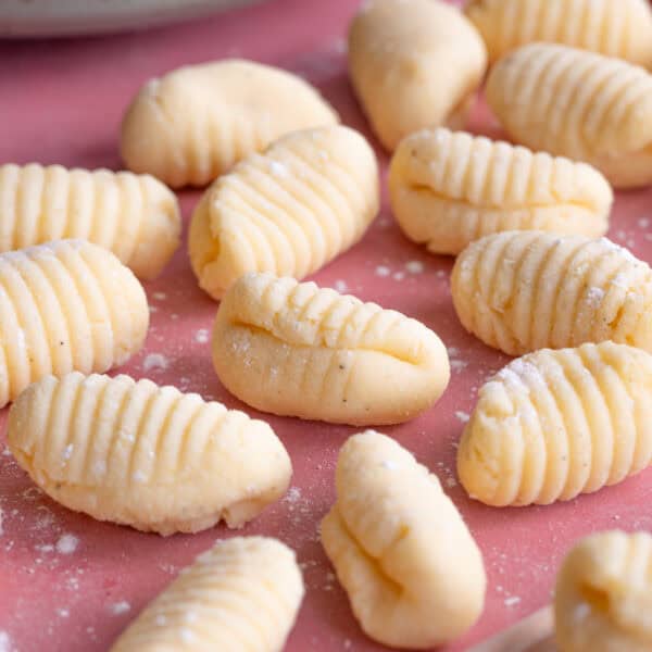 Close up shot of gluten free gnocchi on a pink worktop.