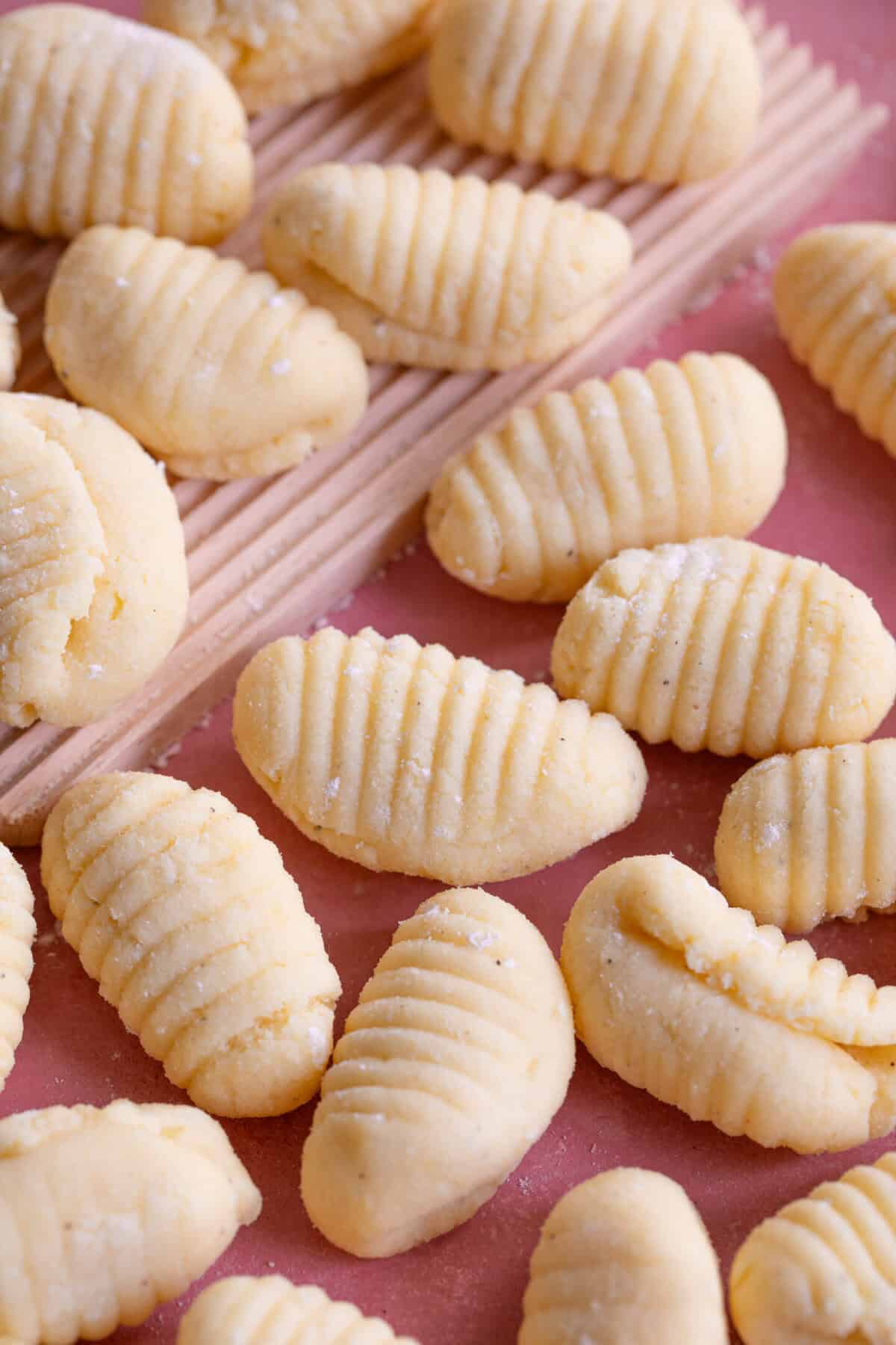 Close up shot of gluten free gnocchi on a pink worktop.
