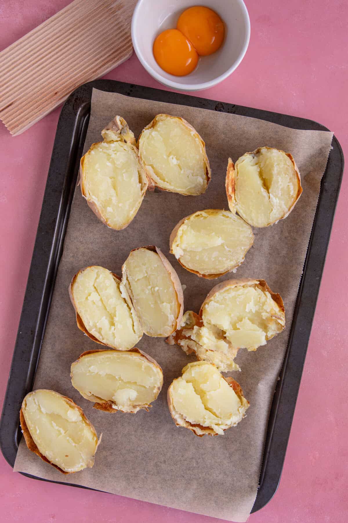 Gluten free gnocchi recipe process shot showing how to cut the cooked potatoes in half and scrape out the flesh.