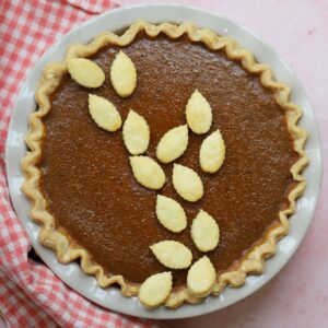 A gluten free pumpkin pie on a pink backdrop.