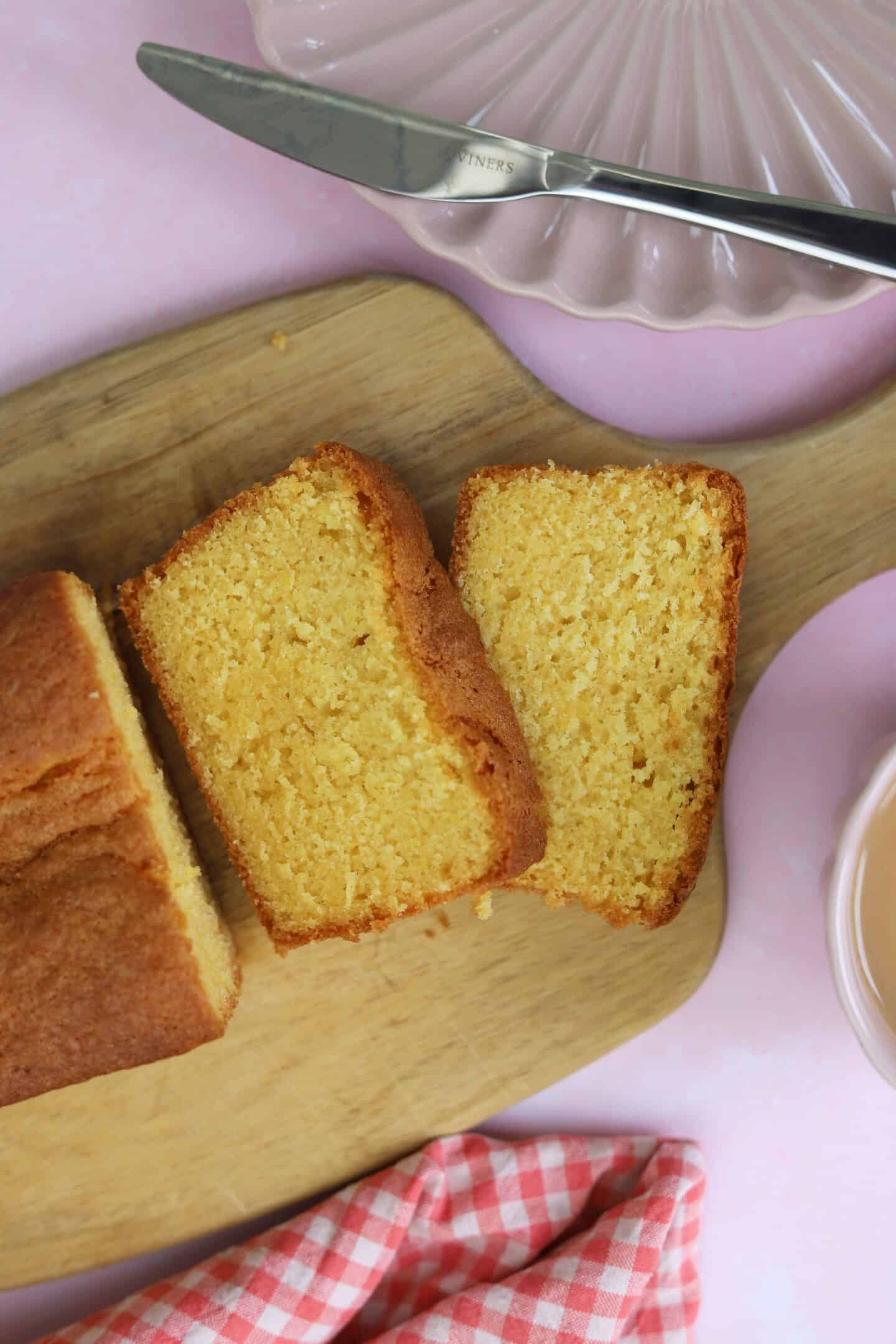 A sliced gluten free Madeira cake on a wooden chopping board.