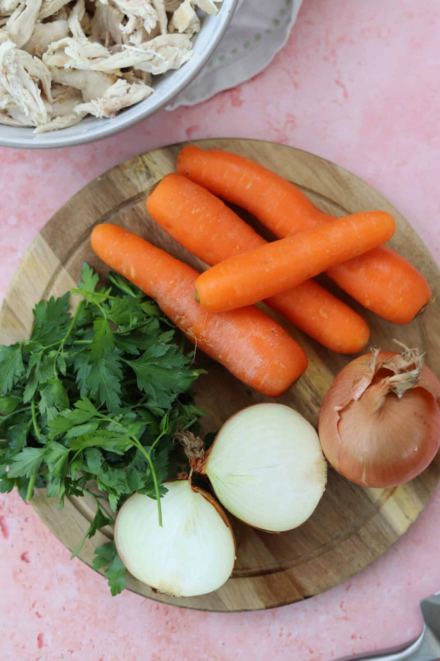vegetables for gluten free chicken stock - carrots, onion and parsley on a wooden chopping board