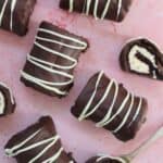 Chocolate mini rolls on a pink worktop.