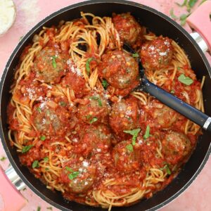 A pan of meatballs and spaghetti with marinara sauce.