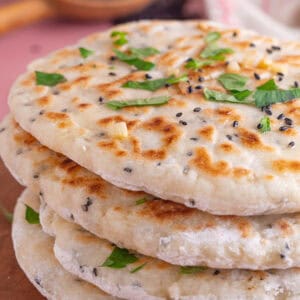 A stack of gluten free naan breads topped with chopped coriander.
