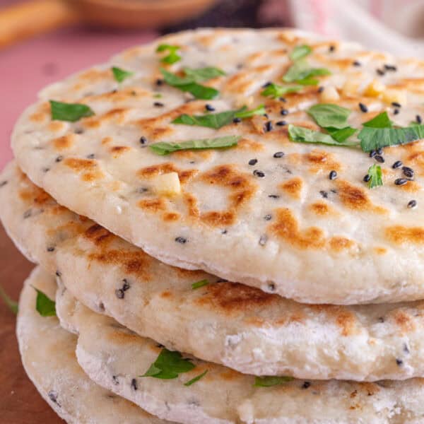 A stack of gluten free naan breads topped with chopped coriander.
