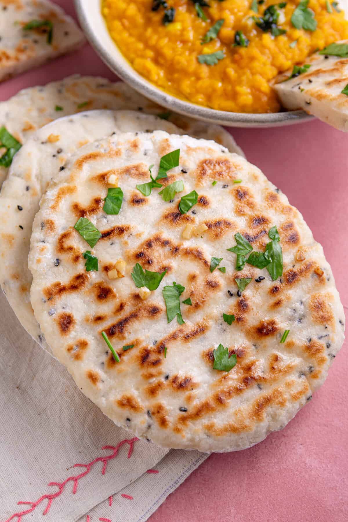 A stack of gluten free naan bread next to a lentil curry.
