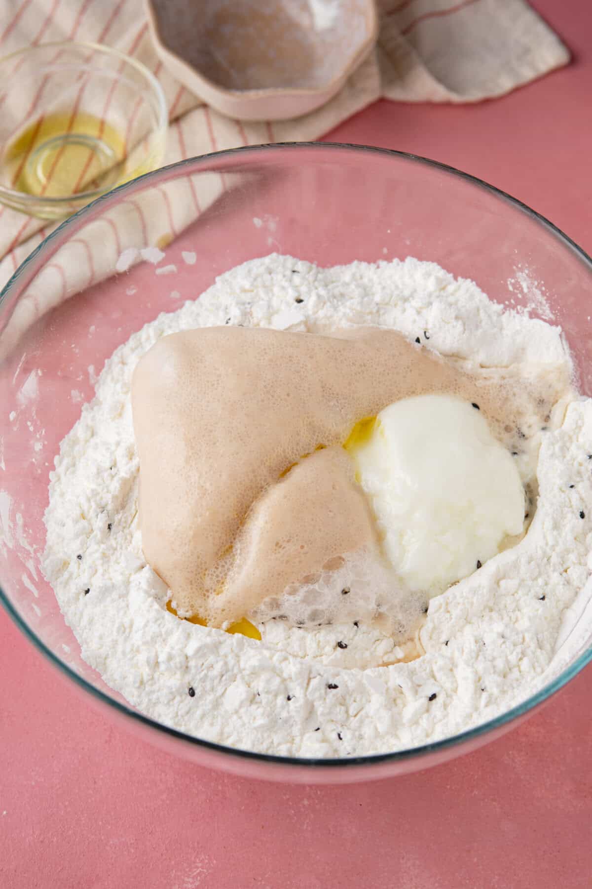 Process shot for gluten free naan bread recipe showing the wet ingredients added to the dry ingredients.