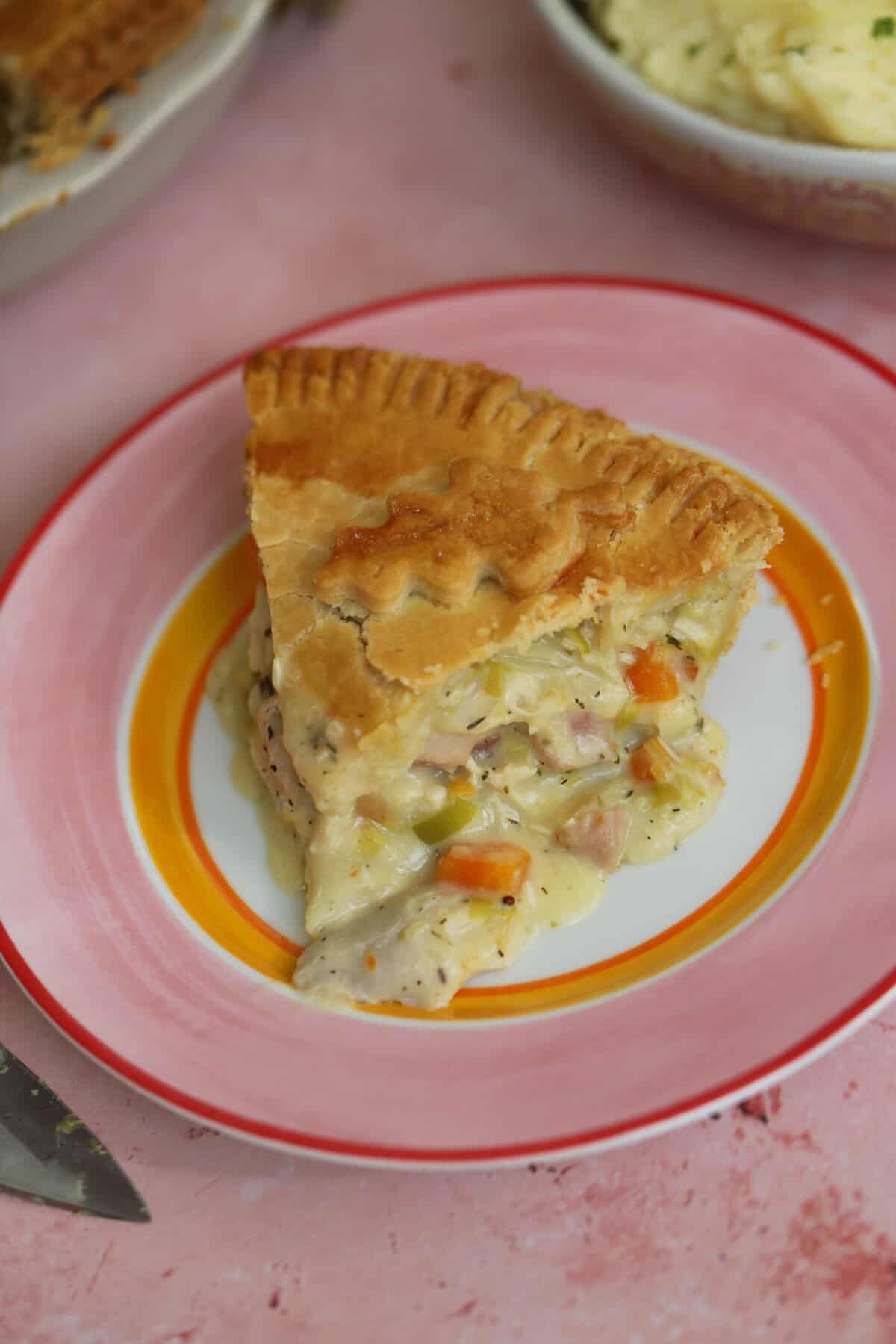 A slice of chicken and ham pie on a plate.