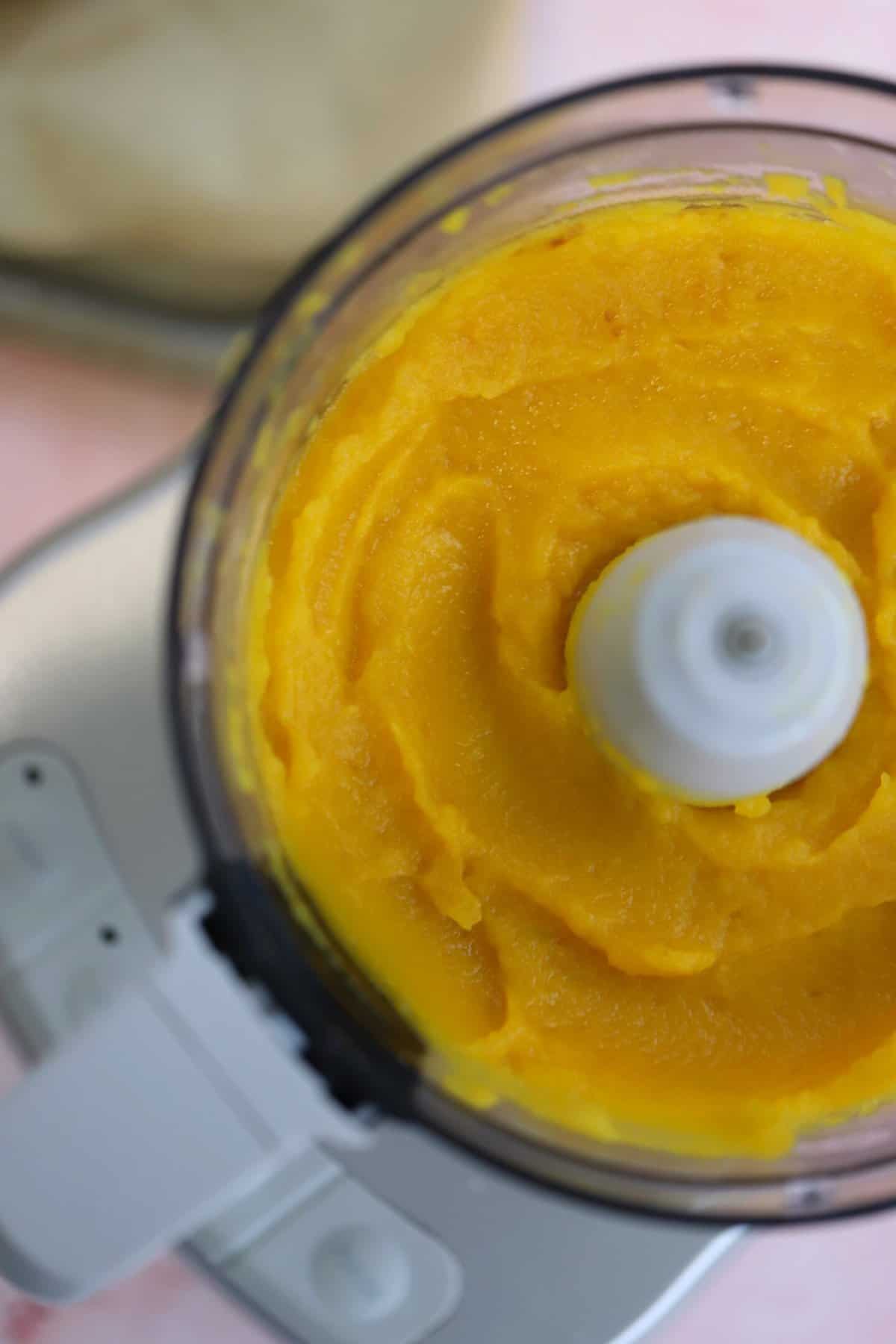 A food processor filled with pumpkin puree.
