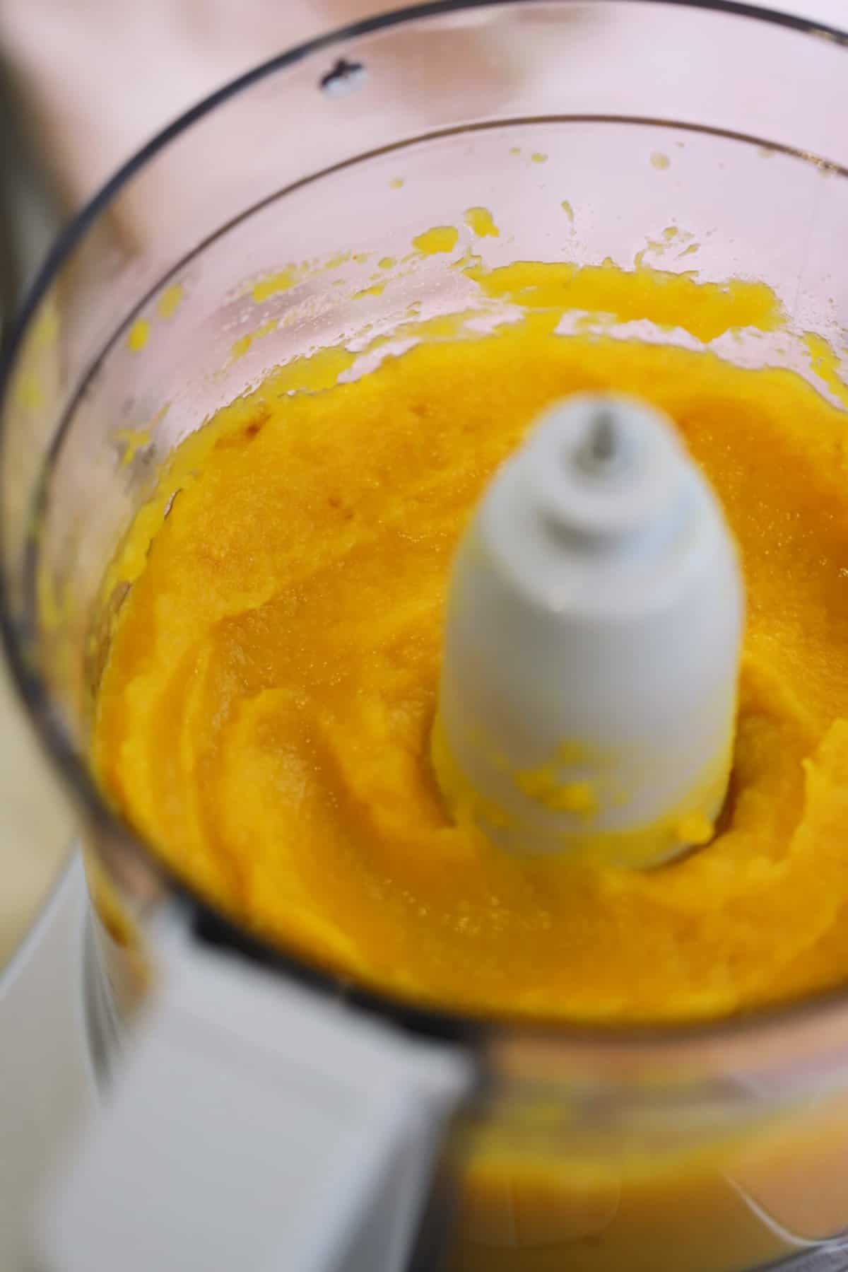A food processor filled with pumpkin puree.