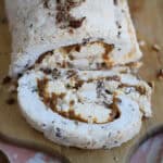A toffee and pecan meringue roulade on a wooden board.