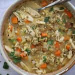 A bowl of leftover turkey soup with a spoon and stuffing sprinkled on top.