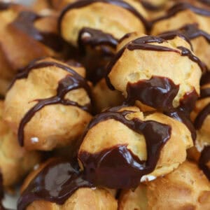 A plate of gluten free profiteroles drizzled with chocolate sauce.
