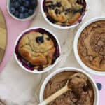 A selection of white ramekins containing either chocolate baked oats or blueberry baked oats.