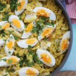A pan of kedgeree with rice, smoked fish and eggs and parsley on top.