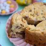 A Mini Egg Cookie Pie with a wedge taken out of it, on a pink plate.