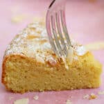A fork taking a piece out of a slice of almond flour cake.
