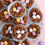 A plate full of chocolate easter nests on a pink backdrop.