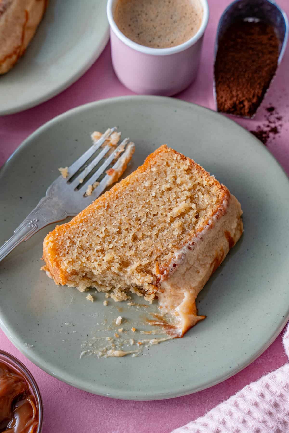 A slice of caramel latte cake on a plate with a piece bitten off.