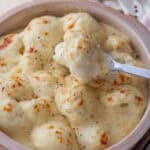 A dish of gluten free cauliflower cheese with a spoonful scooped out.