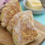 Gluten free Irish soda farls on a wooden board with butter in the background.