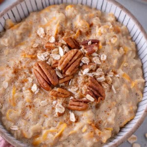 A bowl of carrot cake porridge topped with pecan nuts.