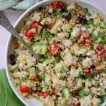 A bowl of couscous salad with turkey, tomato, cucumber, pistachios and cranberries.