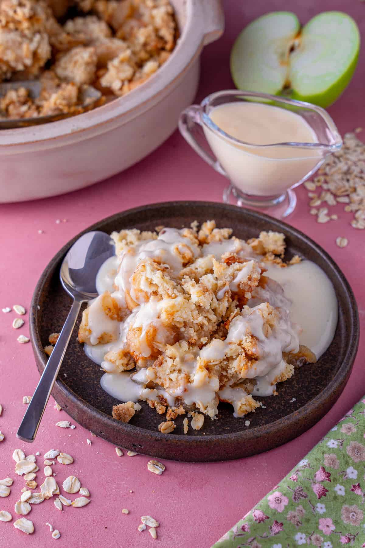 A bowl of gluten free apple crumble with custard.