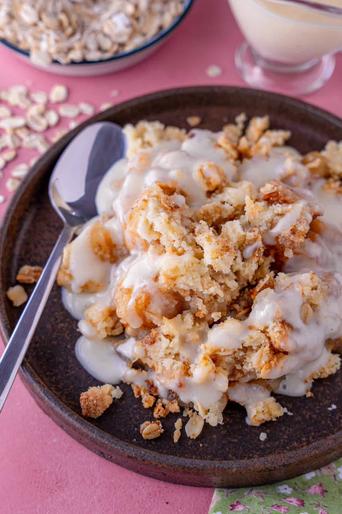 A plate of gluten free apple crumble with custard on top.