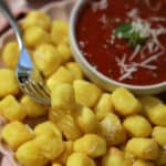 A plate of crispy air fryer gnocchi with marinara sauce and pesto for dipping.