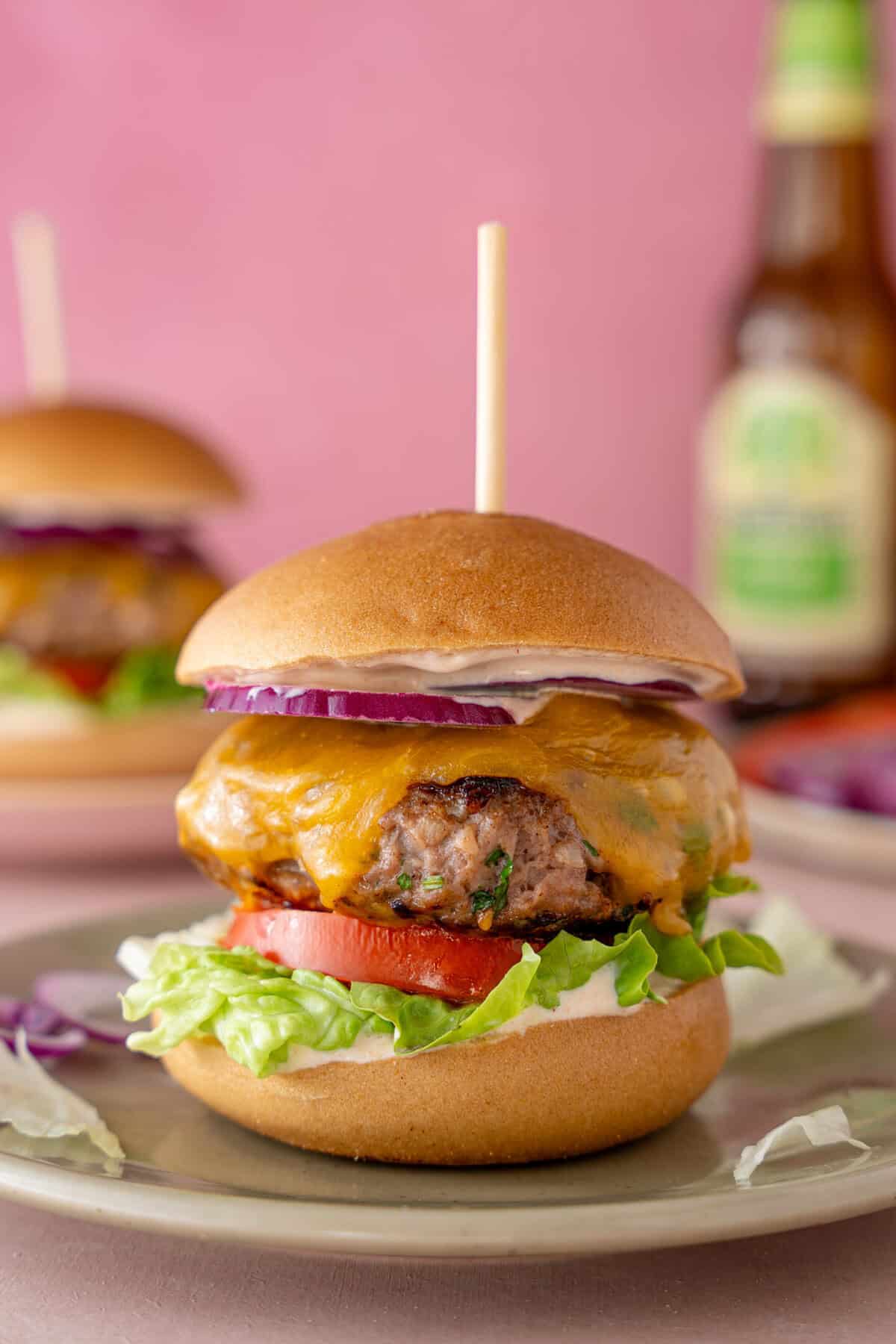 A gluten free beef burger with lettuce, red onion, tomato and cheese.