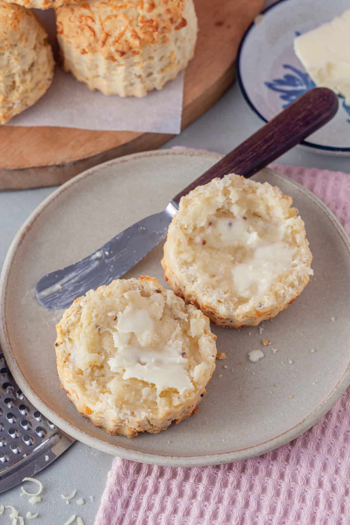 A gluten free cheese scone cut in half and spread with butter.
