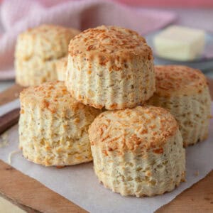 A pile of gluten free cheese scones on a wooden board.
