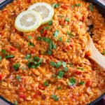 A pan of chorizo risotto garnished with lemon and parsley.