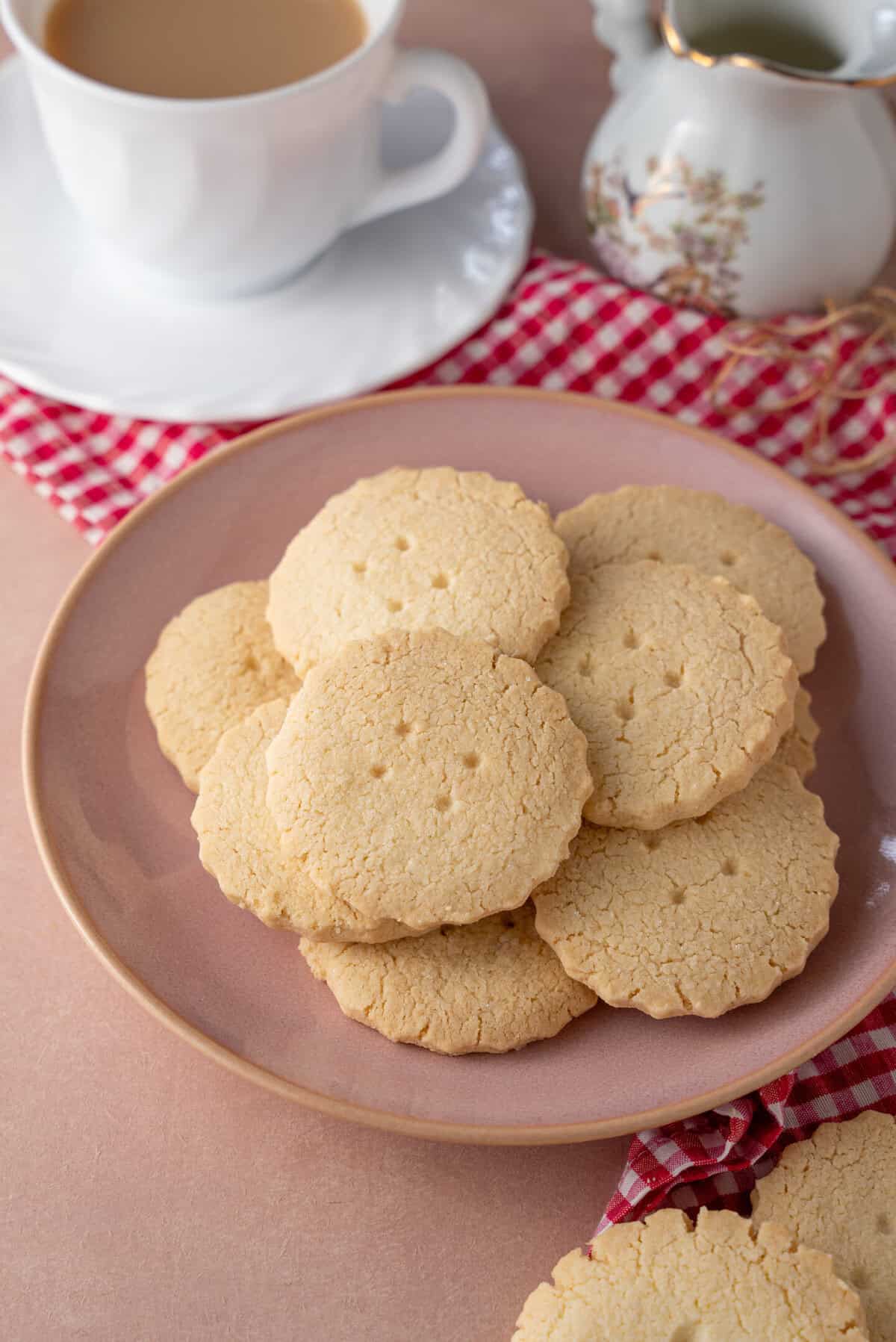 A plate of gluten free shortbread cookies with a cup of tea in the background.