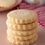 A stack of gluten free shortbread biscuits on a pink worktop.