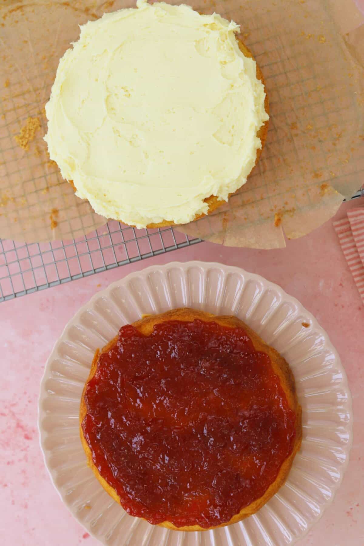Spread jam on one sponge and buttercream on the other.