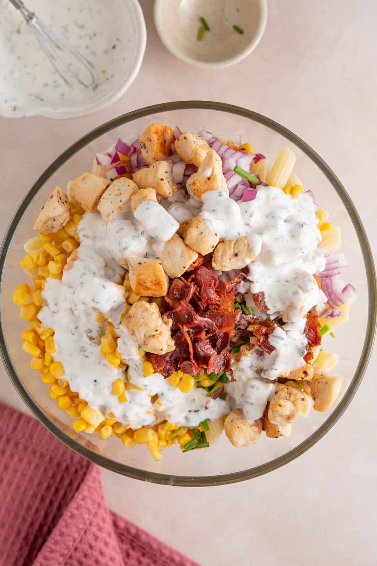 A chicken and bacon pasta salad in a bowl before mixing.