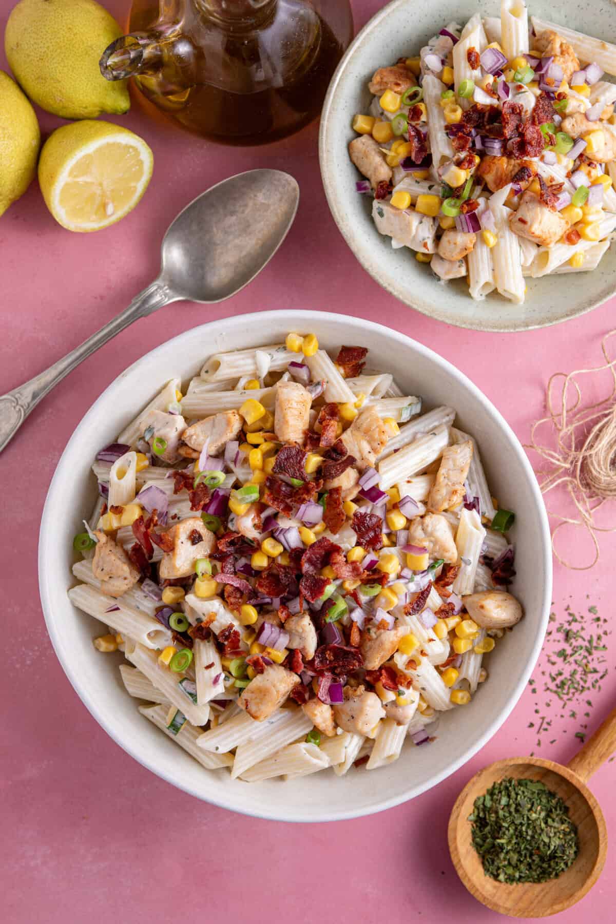 Overhead shot of a bowl of chicken and bacon pasta salad on a pink backdrop.