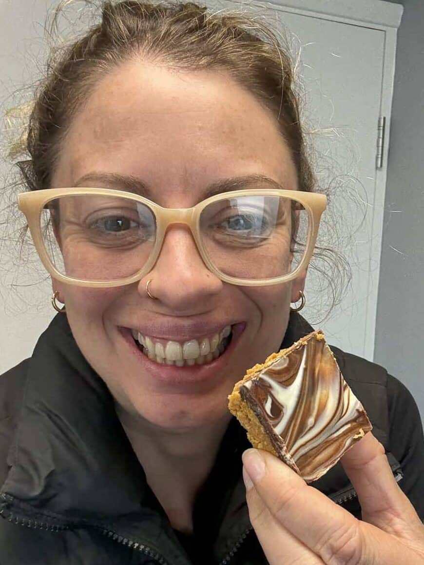 Post author Sarah Howells holding up a cereal bar and smiling.